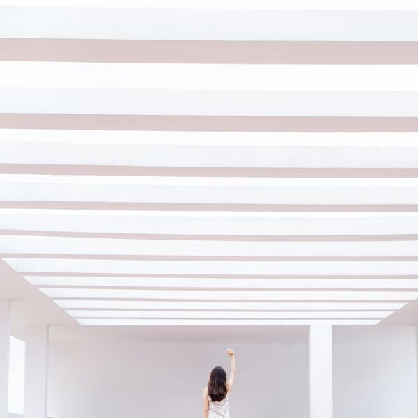 Person practicing a gentle stretching movement in a bright, airy space.